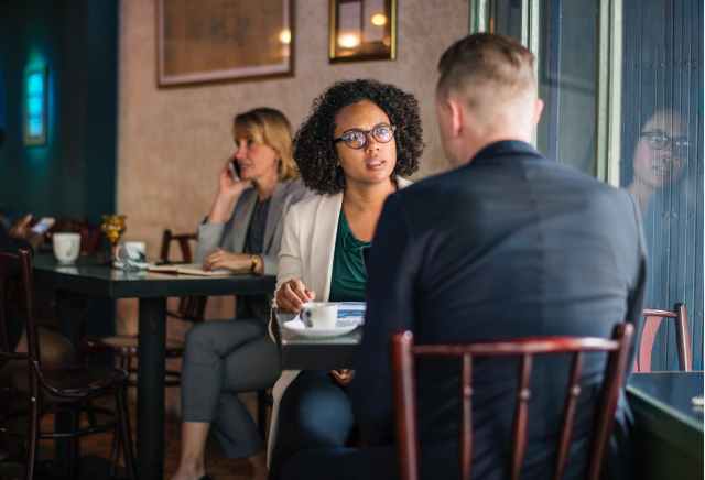 man wearing suit jacket sitting on chair in front of woman wearing eyeglasses