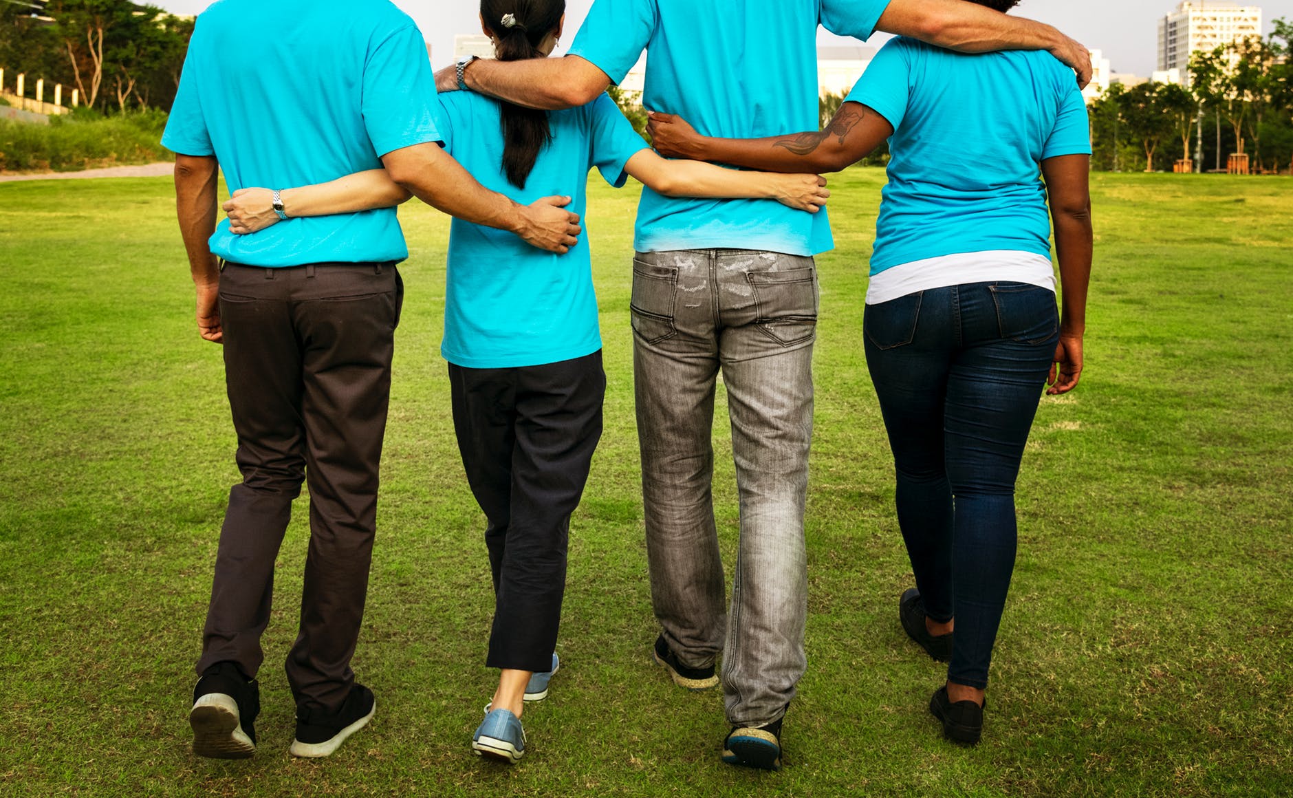 four people walking while holding each others arms