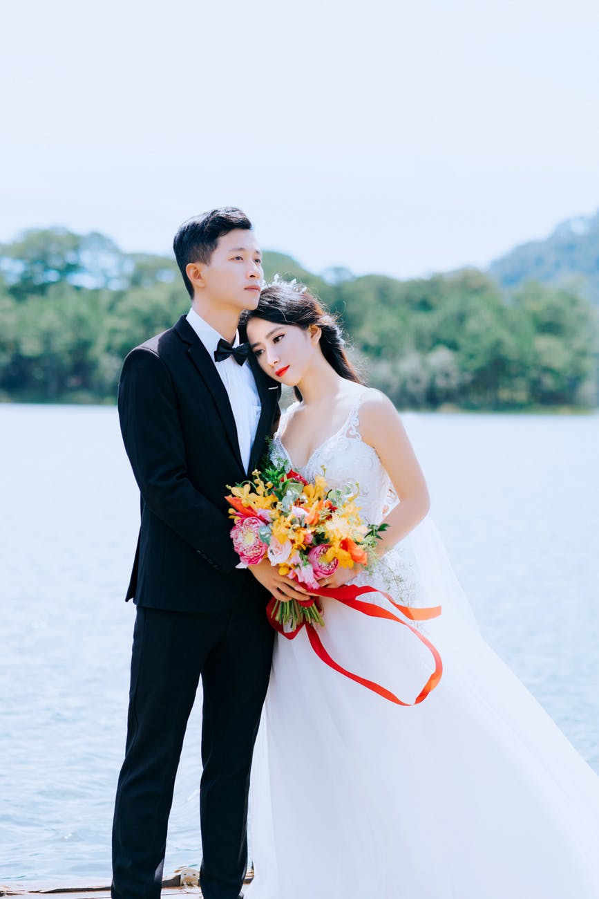 photo of couple standing near body of water