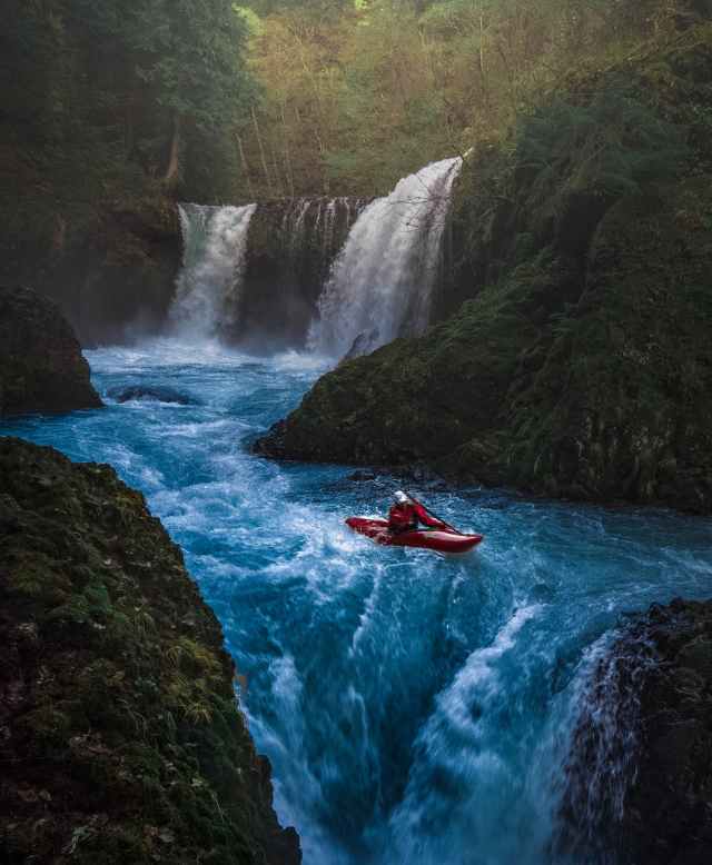 person on watercraft near waterfall