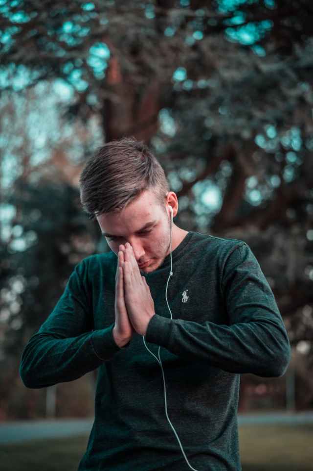 man in green sweater holding his hands