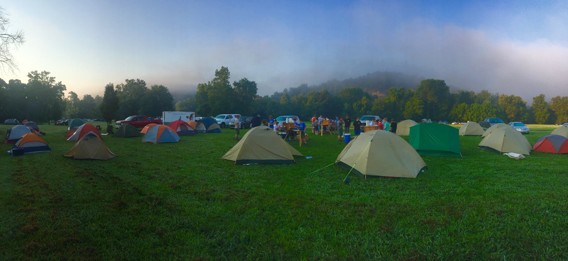 tents on green grass field near mountain