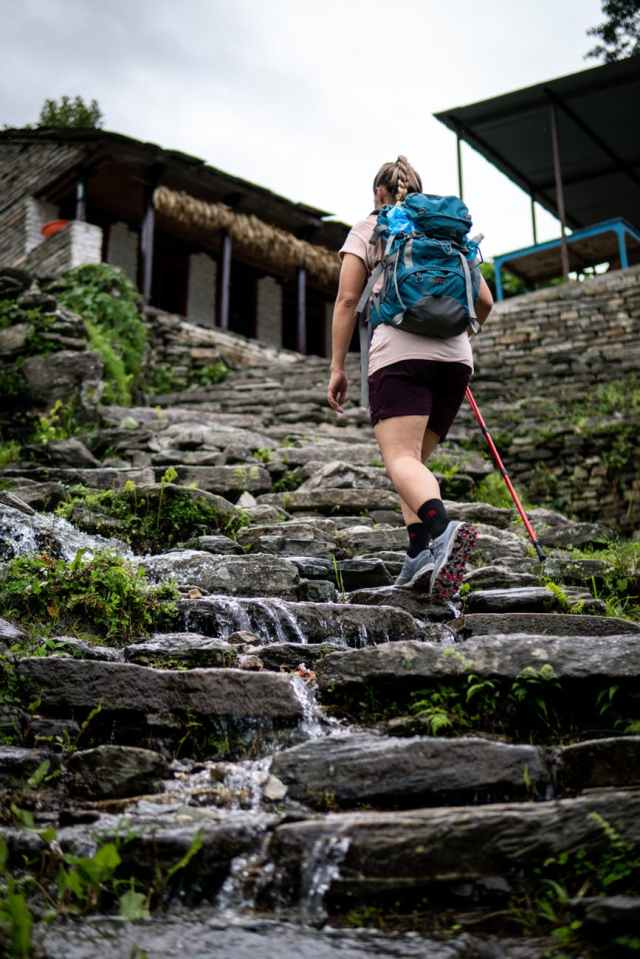 woman carrying black and blue backpack walking on rocky stairs