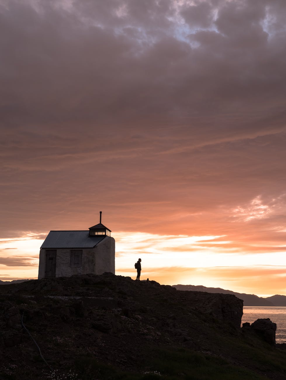 remote house and silhouette on rocky seashore