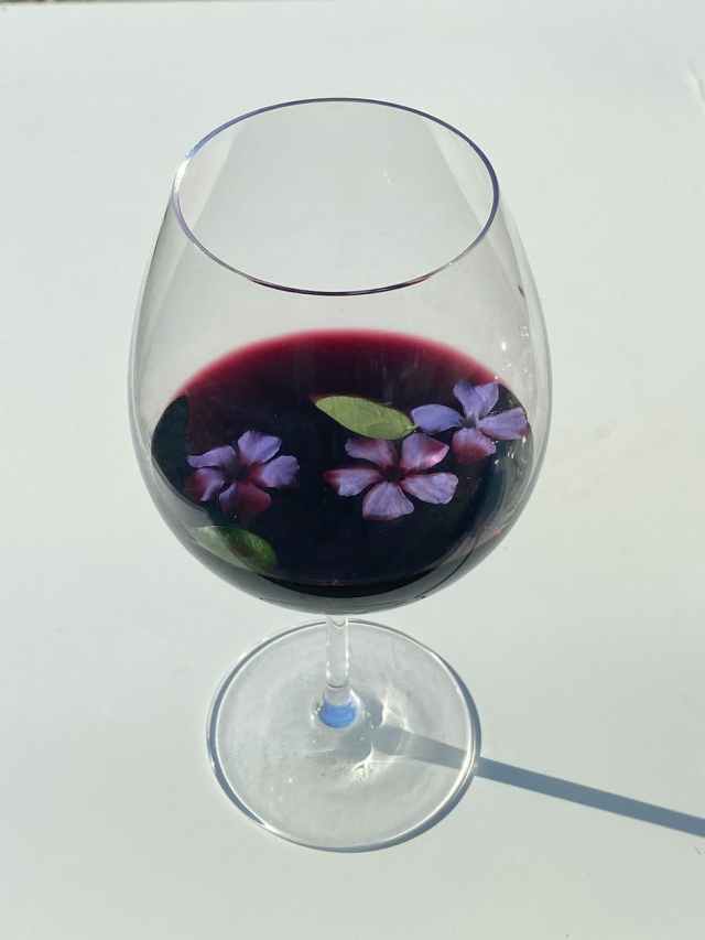 glass of red wine decorated purple flowers