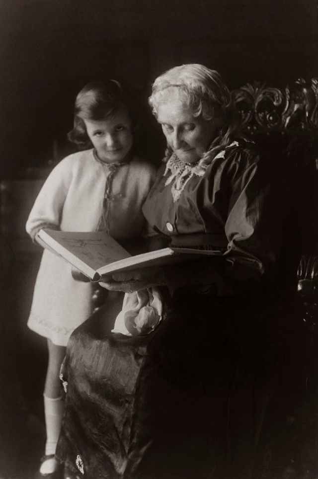 old woman sitting on chair near girl while reading a book