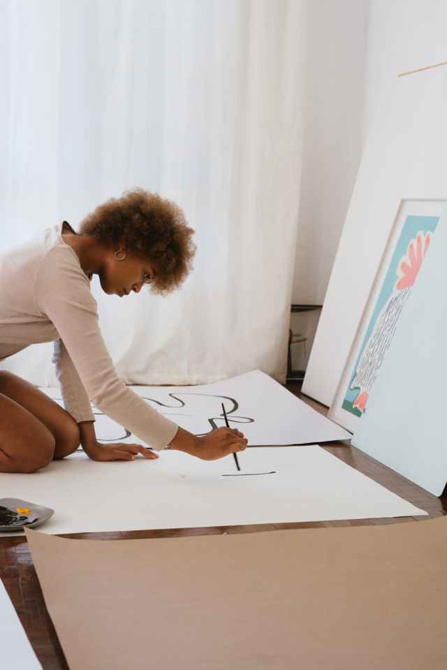 photo of woman painting on white illustration board